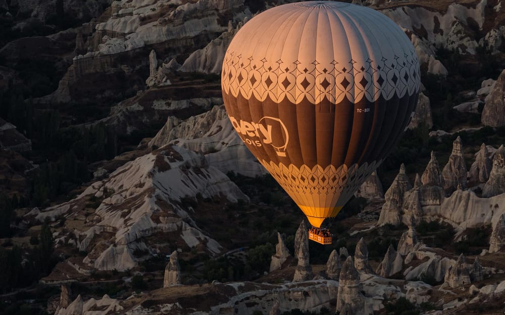 A hot air balloon floating beside Cappadocia’s rock formations
