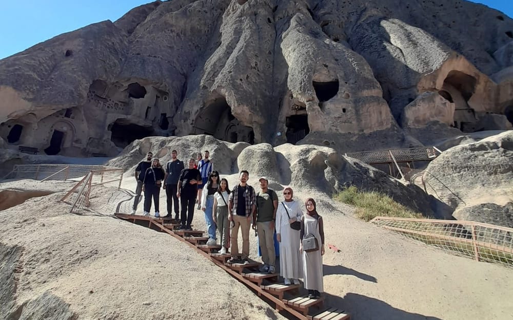 A walking group approaching Cappadocia’s rock-cut buildings