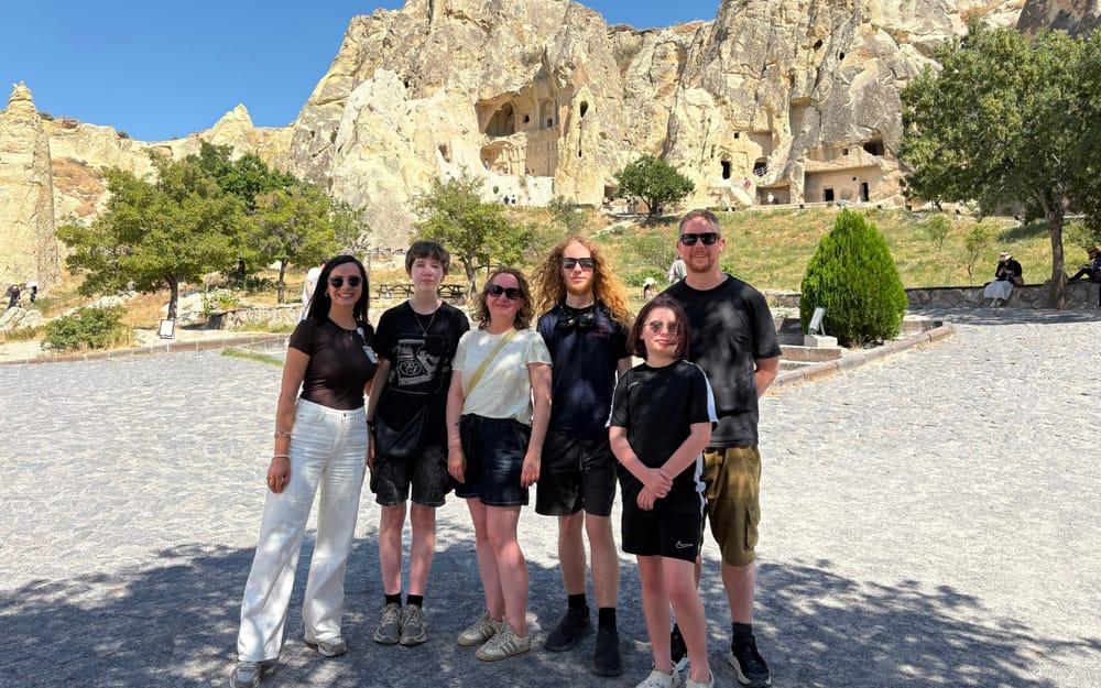 Visitors beside rock-cut buildings on a Cappadocia sightseeing route