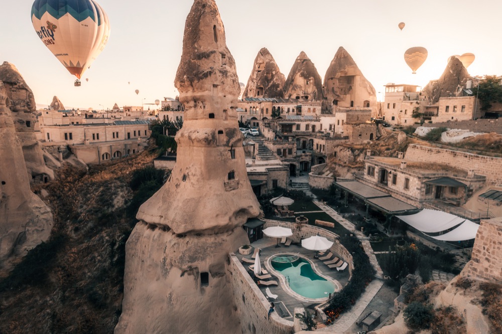 Balloons above Aza Cave Hotel’s pool and fairy chimneys in Göreme