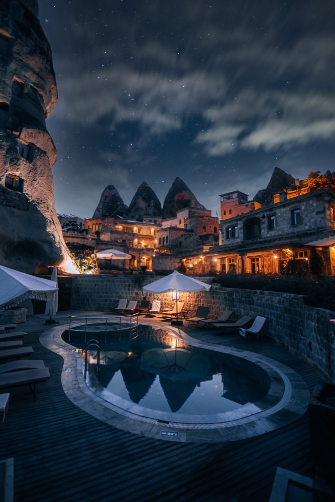 Aza Cave Hotel’s outdoor pool beneath illuminated cave buildings at night