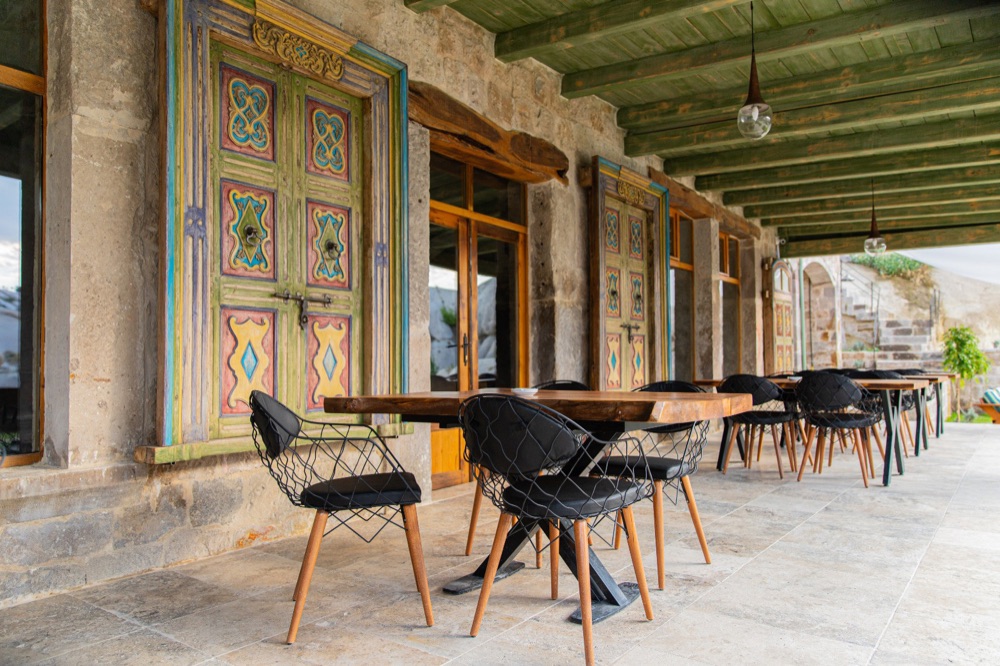 Covered dining terrace with colorful wooden shutters at Aza Cave Hotel