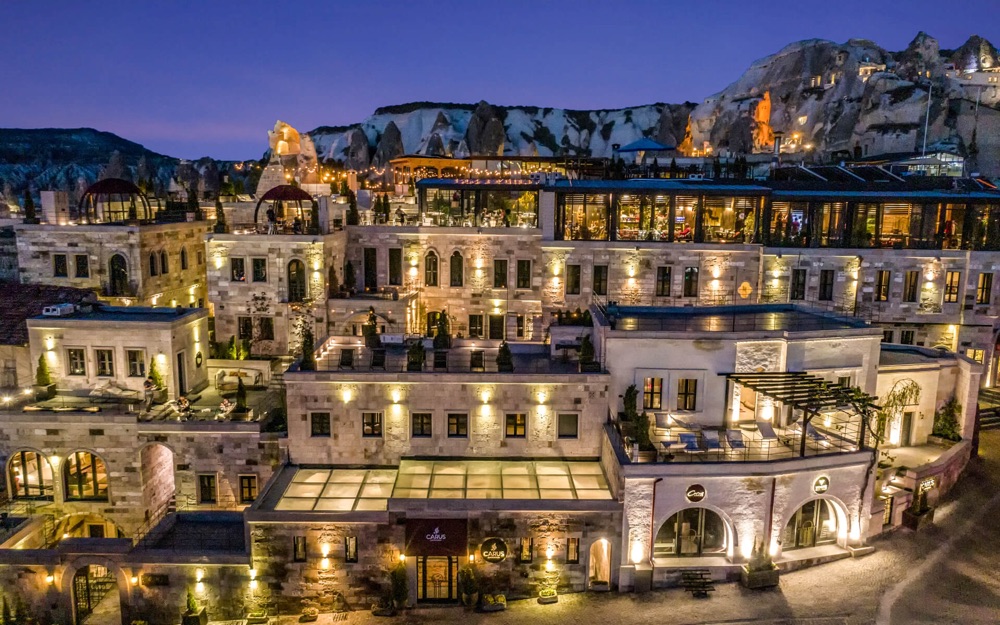 Evening view of Carus Cappadocia’s stone buildings and rooftop restaurant