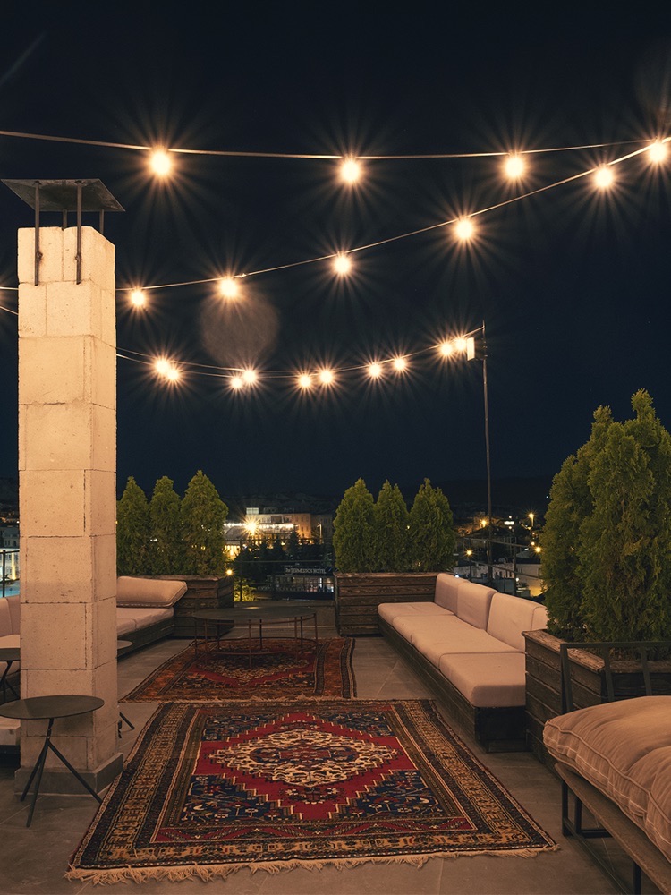 Carus Cappadocia rooftop lounge with patterned rugs and string lights