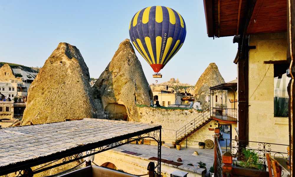 A balloon passing above the terrace rooftops at Kelebek Cave Hotel